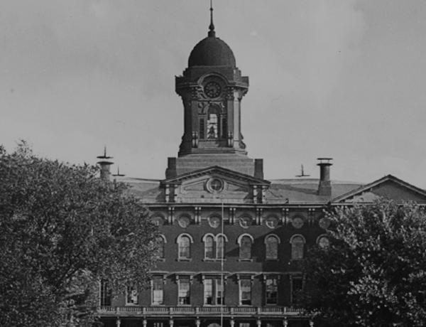 A historic black and white photograph of the original Old Main building with it's bell tower.